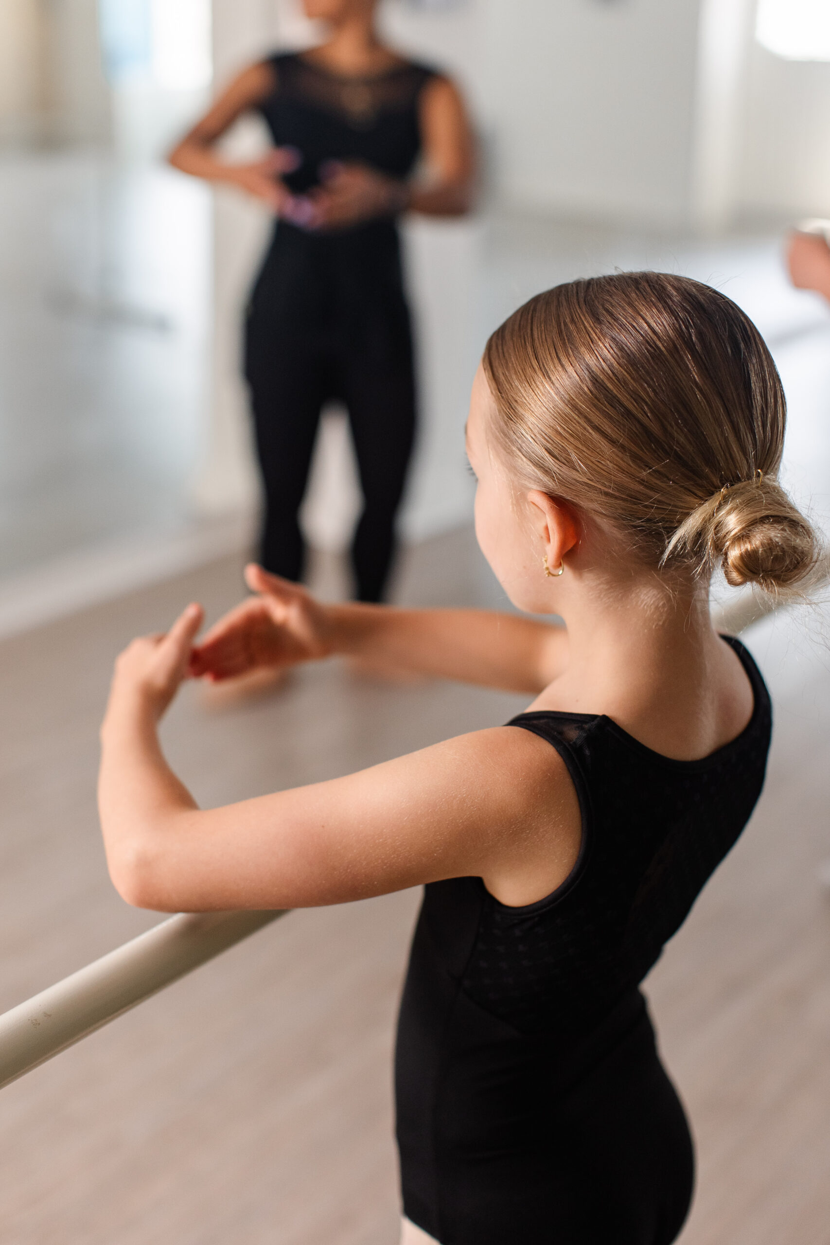 A young dancer places her arms in first position, modeled after her teacher