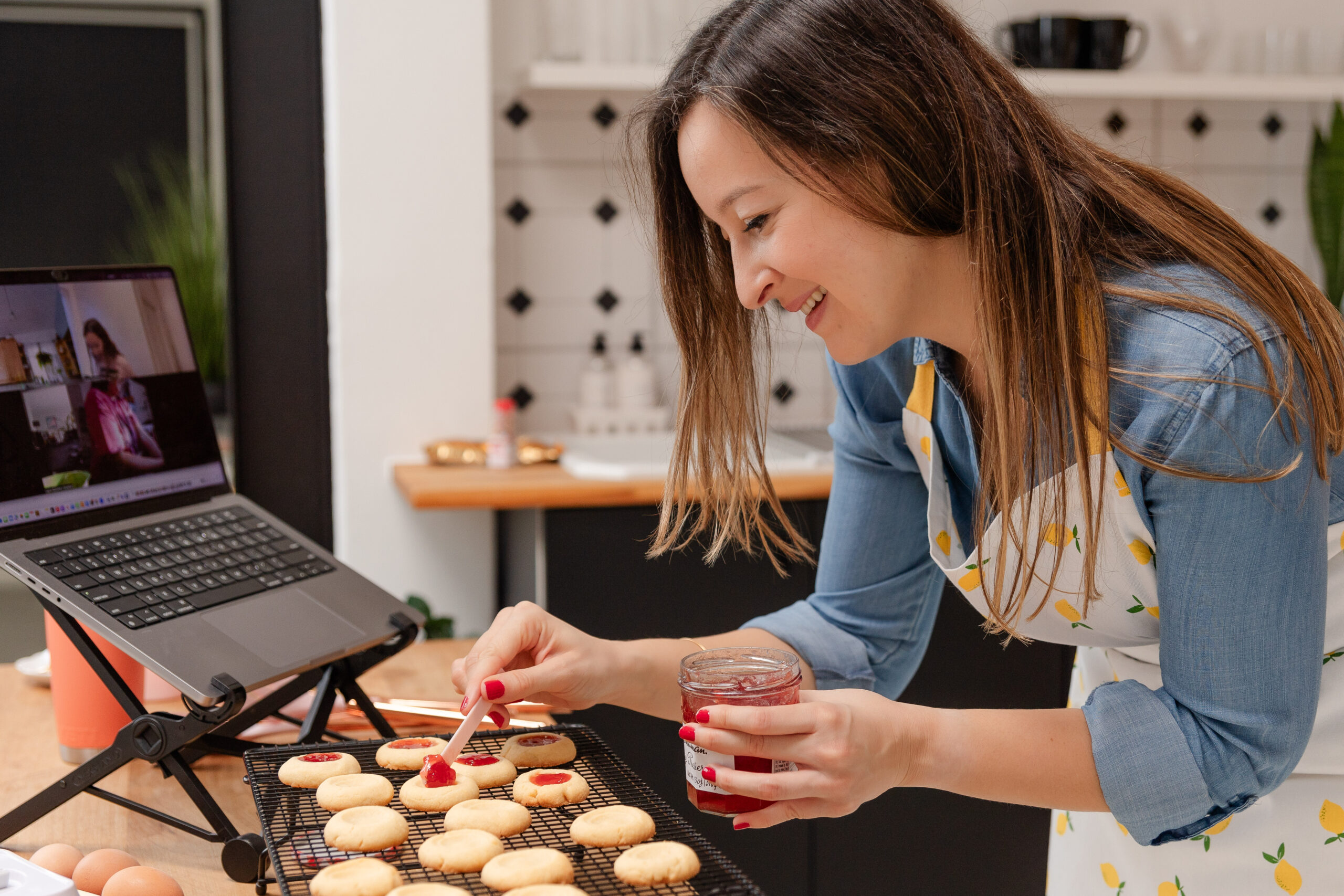 woman baking cookies smiles as she facilitates an online baking event