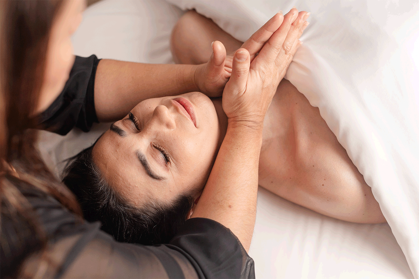 animated gif of a woman of color with a relaxed expression laying on a massage bed receiving a neck massage