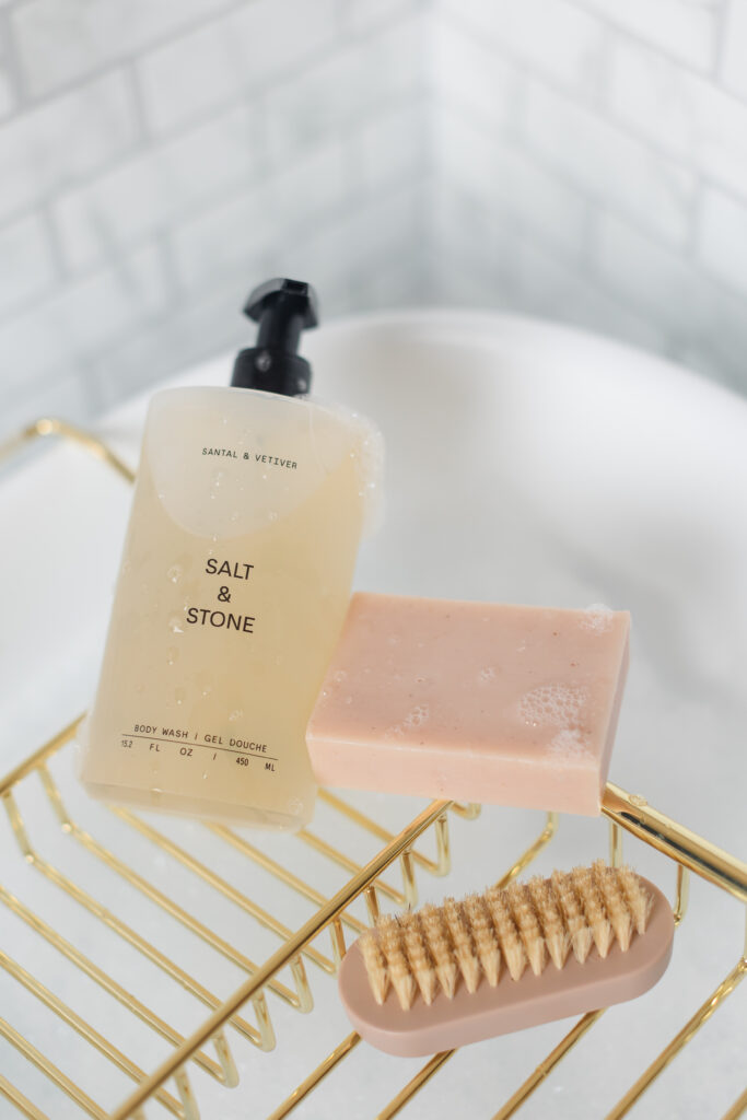 bath products sit on a tray at the edgy of a luxurious white tub, covered in bubbles