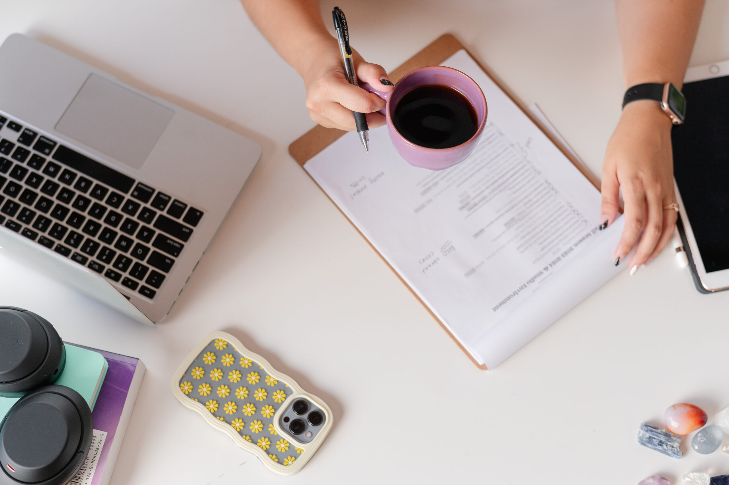 an overhead shot of a desktop featuring crystals, headphones and a cute phone case