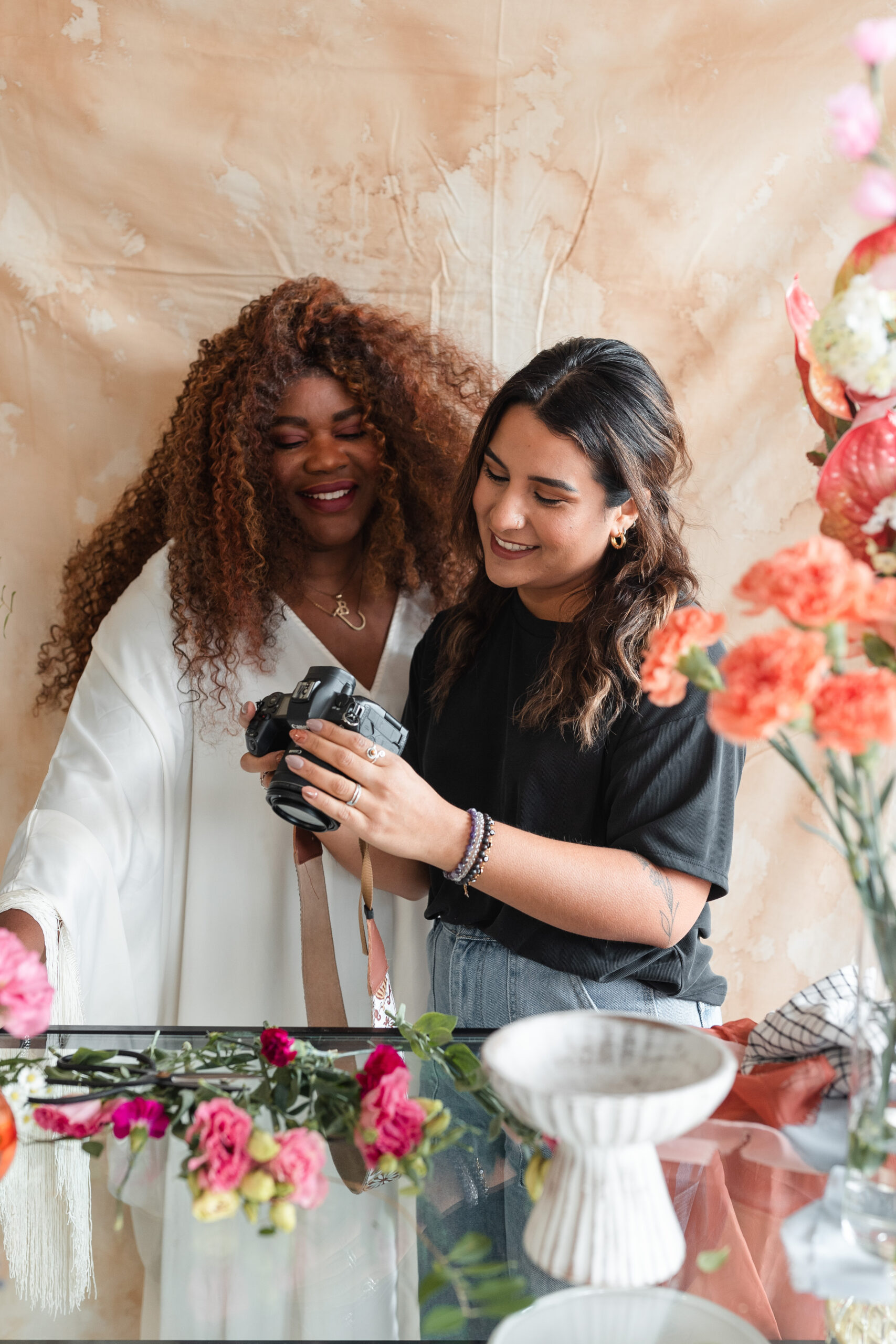 a latina photographer shows her wedding florist client the back of camera at her branding session