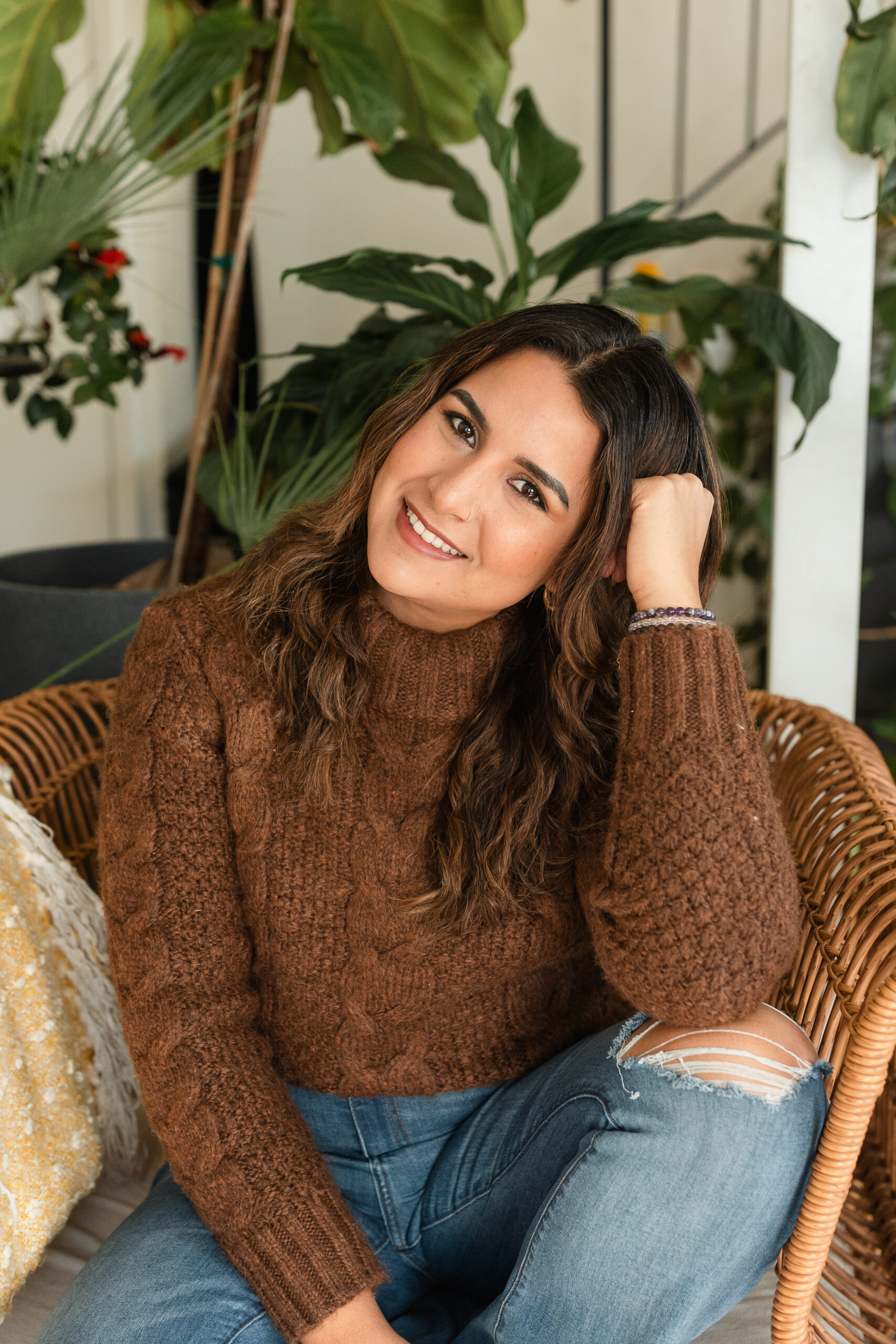 headshot of a latina photographer, sitting casually on a rattan armchair