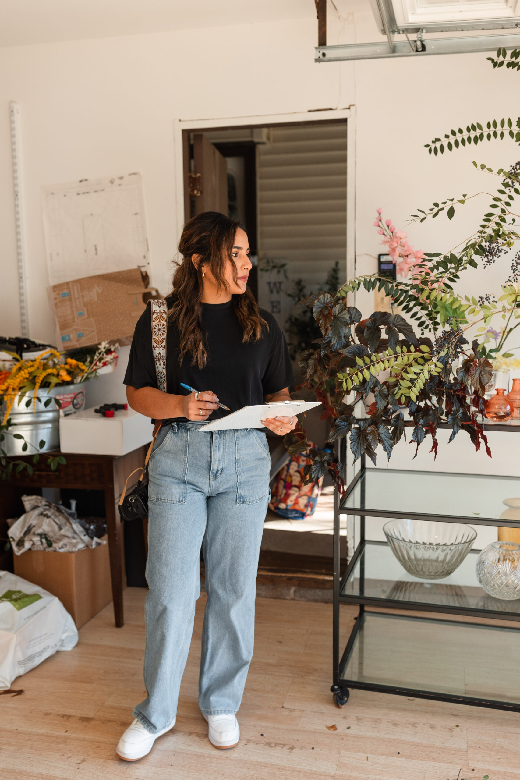 a latina photographer with a clipboard enters a studio space for a client shoot