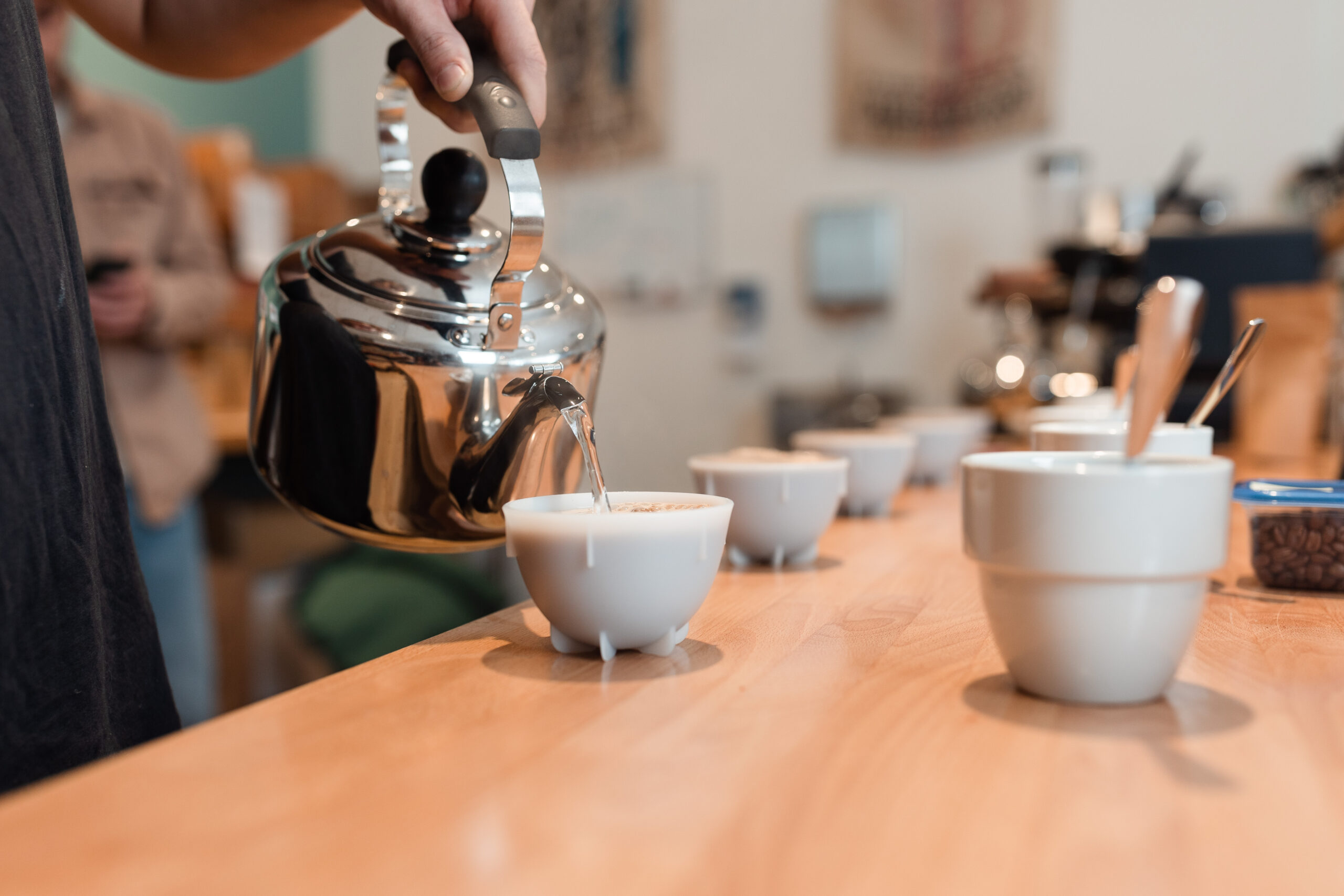 Hot water is poured from a kettle into cupping cups