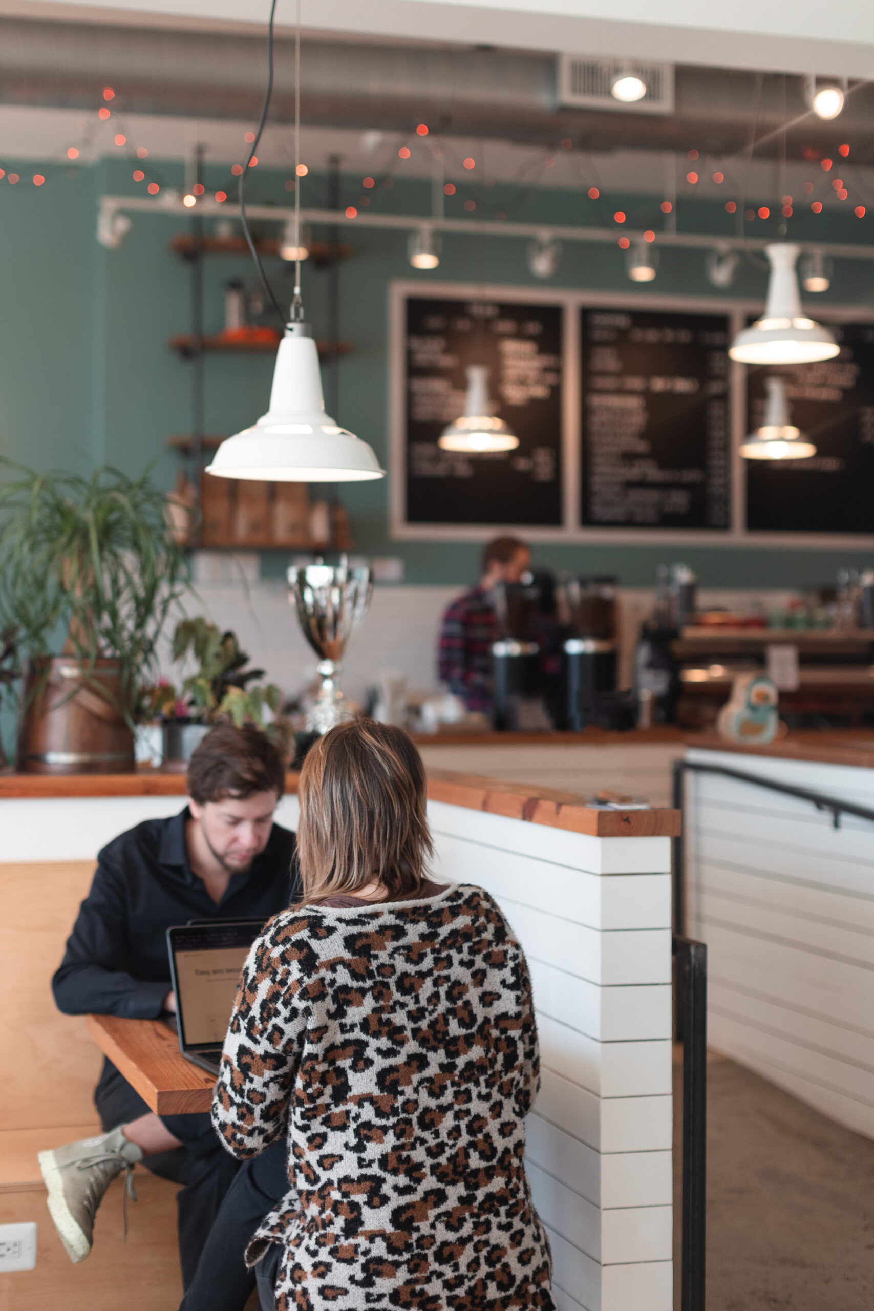 Two people share a table at Rare Bird Coffee Roasters in Falls Church City, Virginia and work in the cozy environment