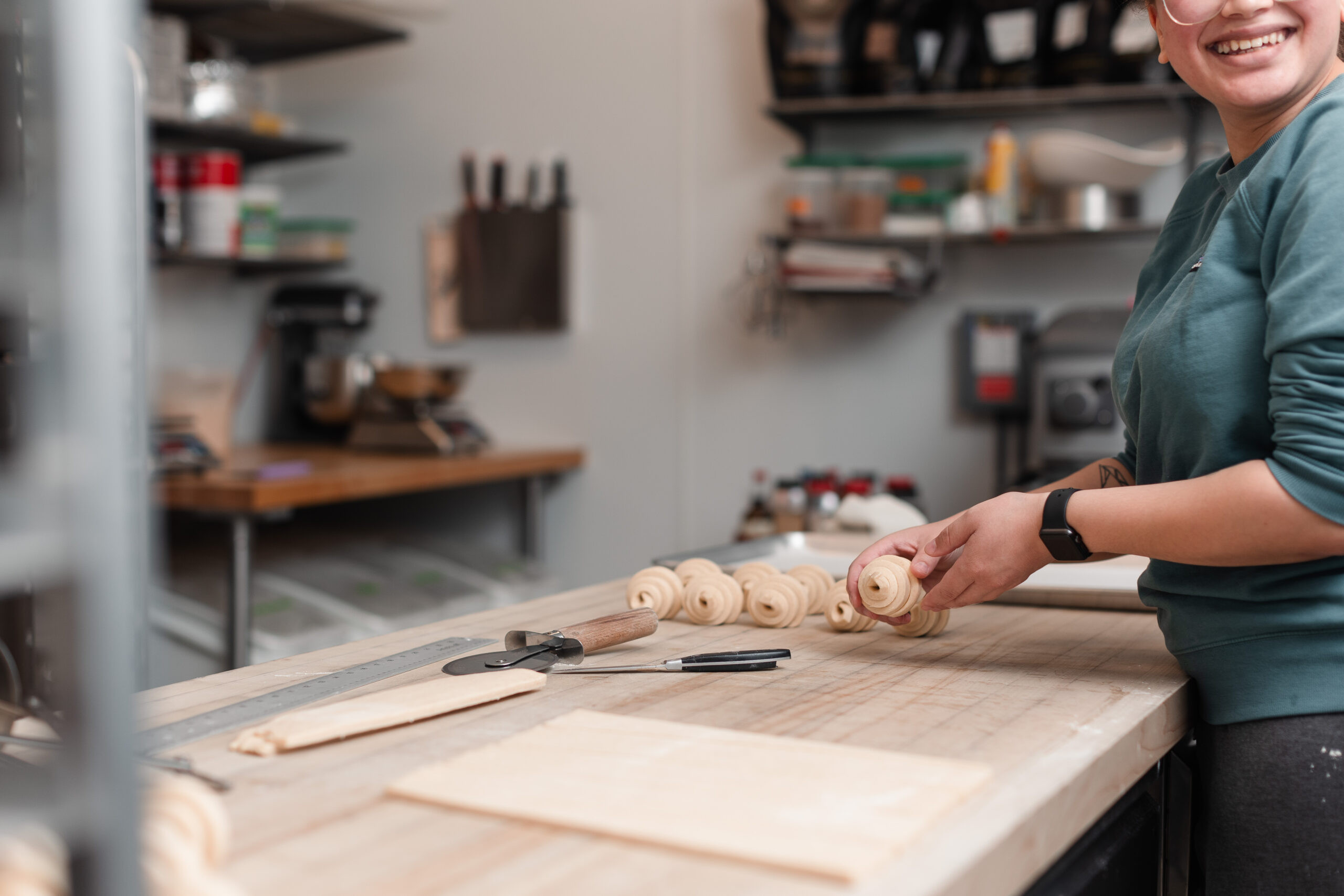 A baker smiles as she makes croissants for a coffee shop