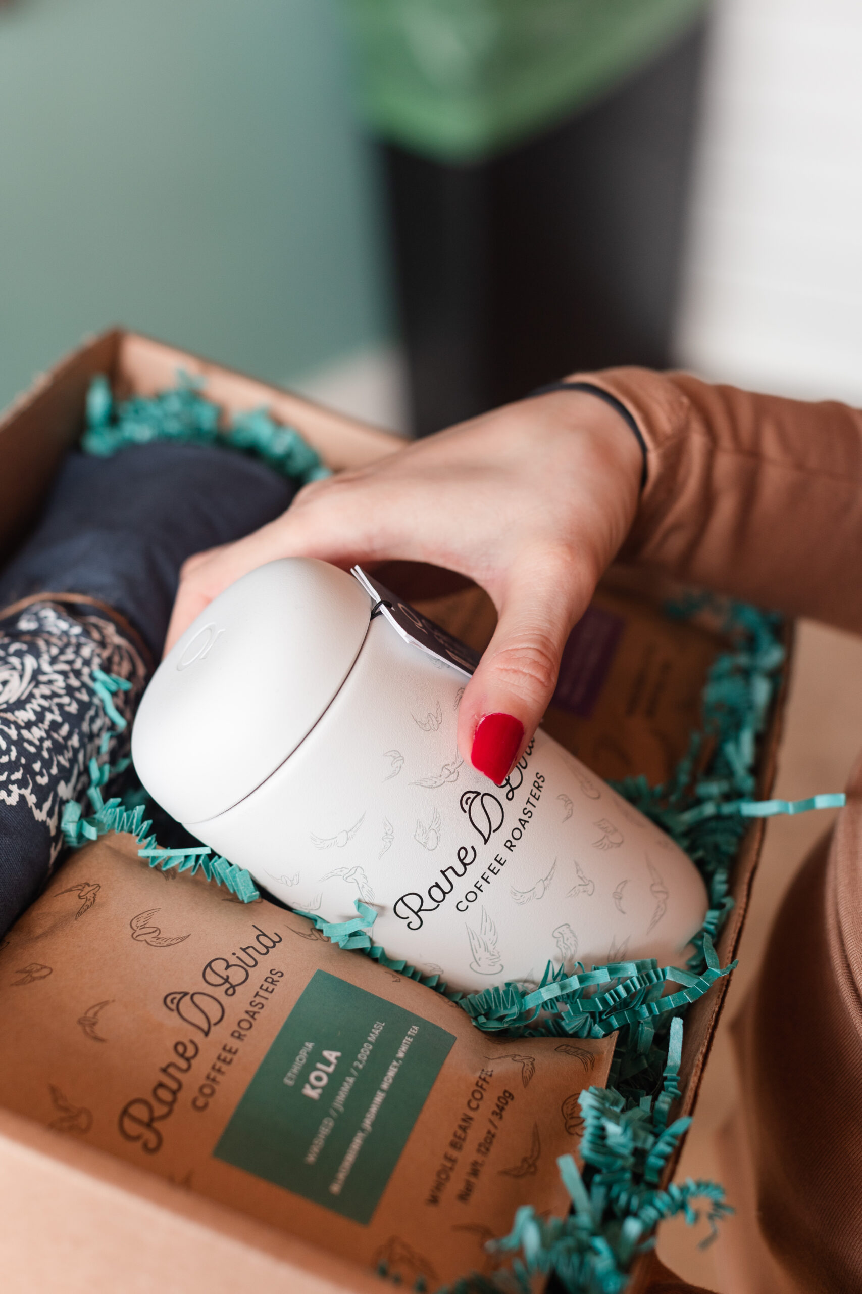 A woman grabs a branded Fellow mug from a Rare Bird Coffee Roasters holiday gift box