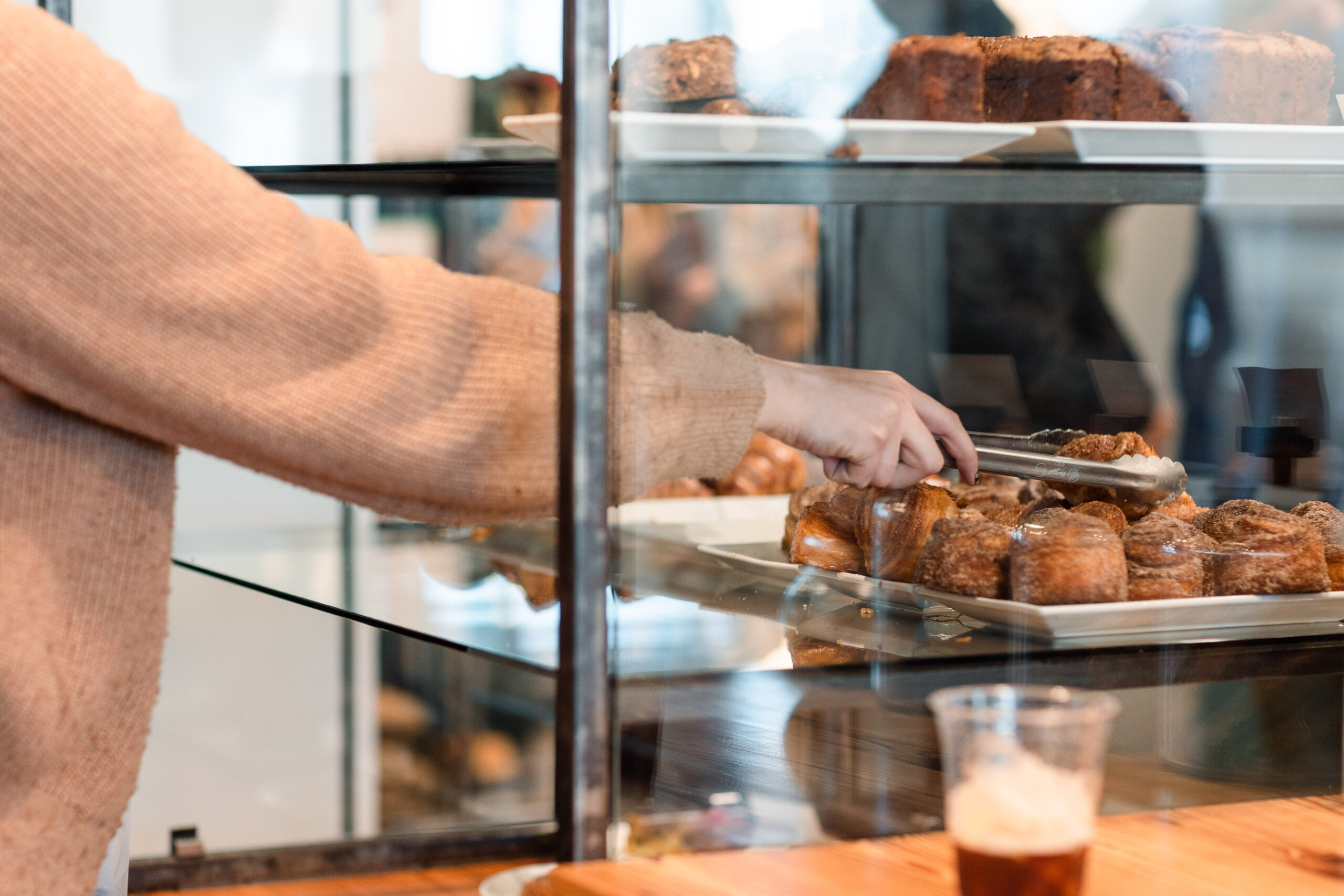 A barista selects a pastry from the case