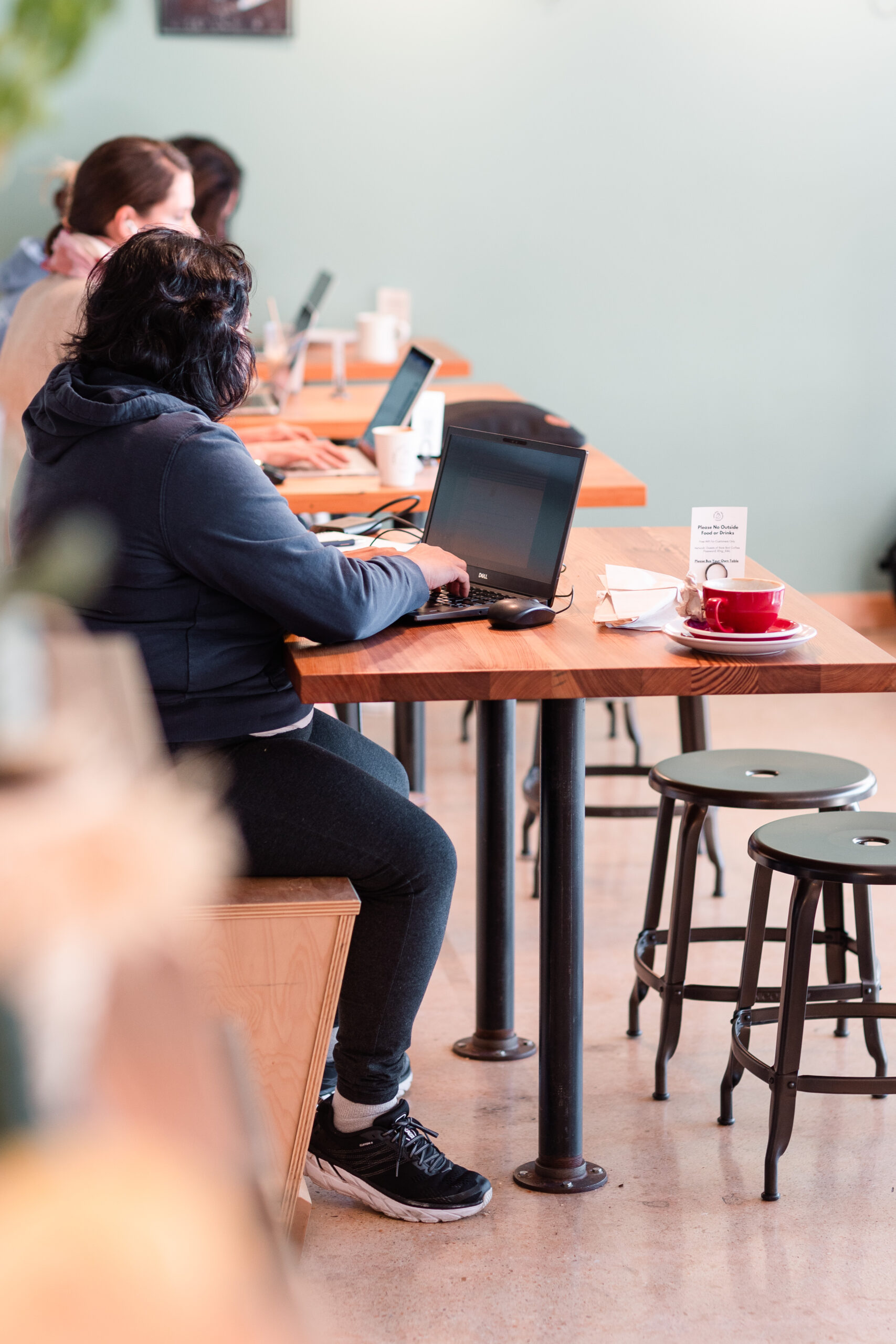 A woman sits at her laptop at Rare Bird Coffee Roasters in Falls Church City, Virginia