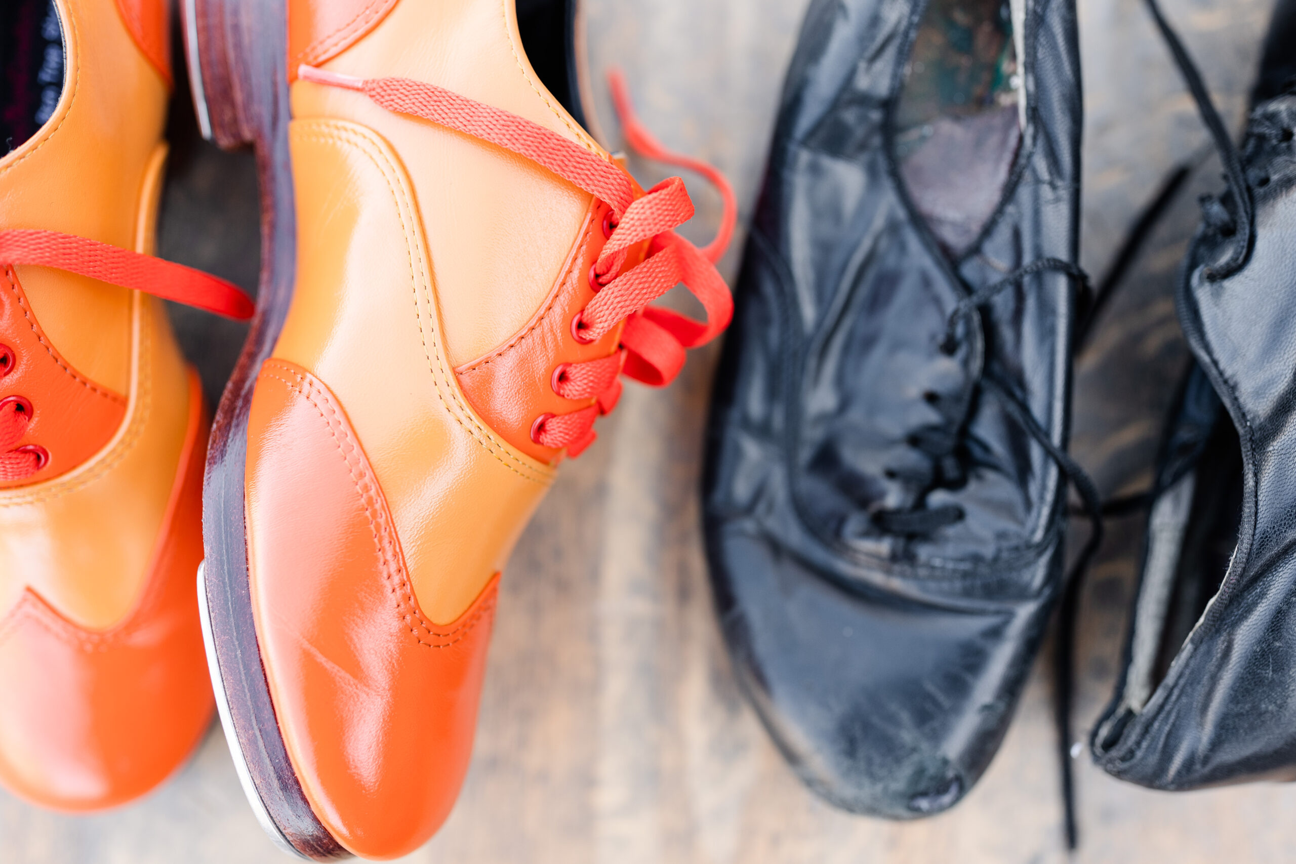 two pairs of well-worn tap shoes on a wooden tap floor