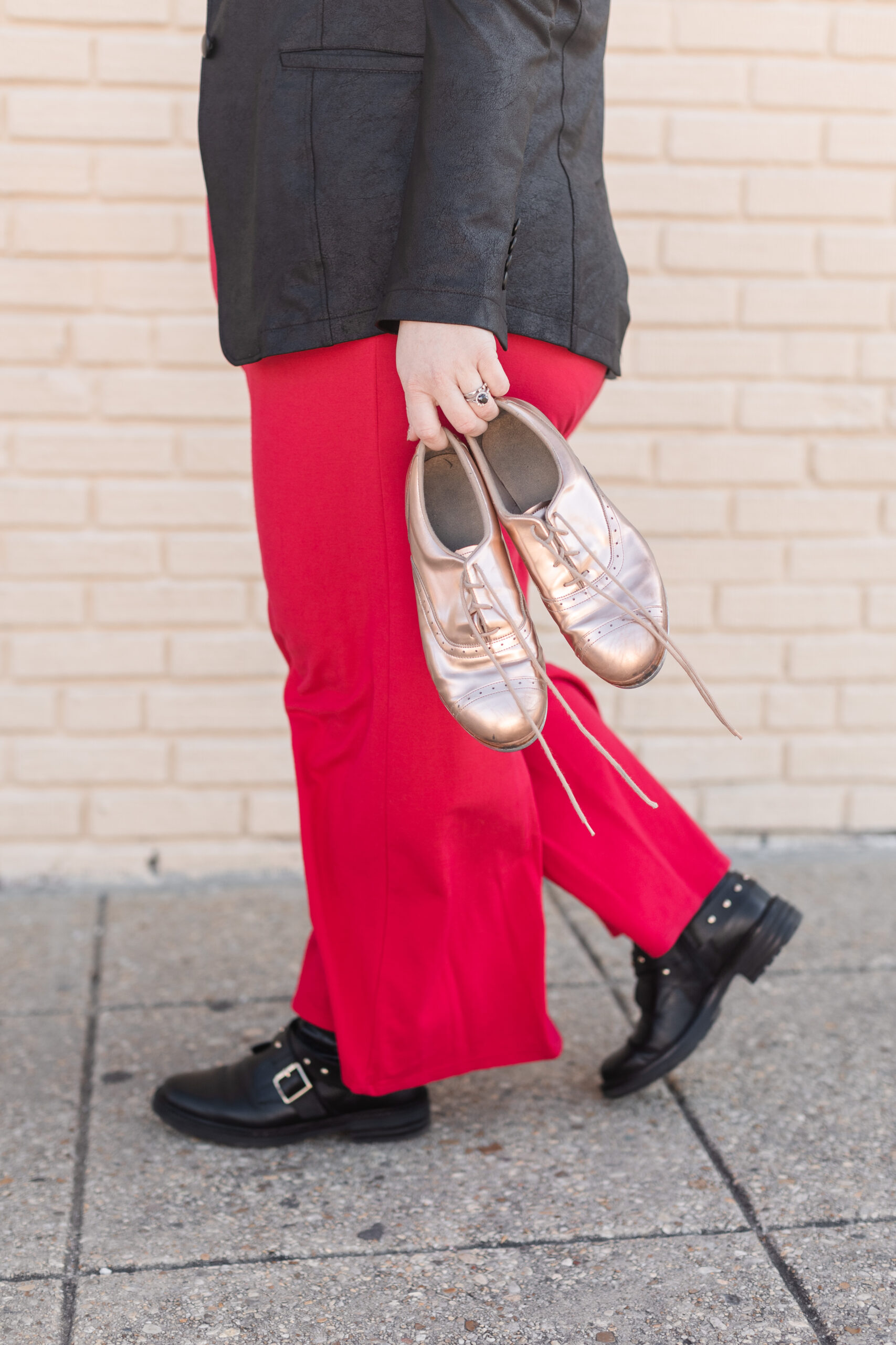 a dance teacher holds gold tap shoes by her side