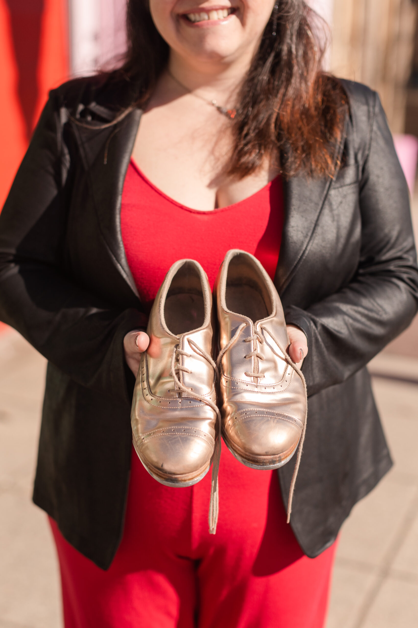 a tap educator holds gold tap shoes in her hands